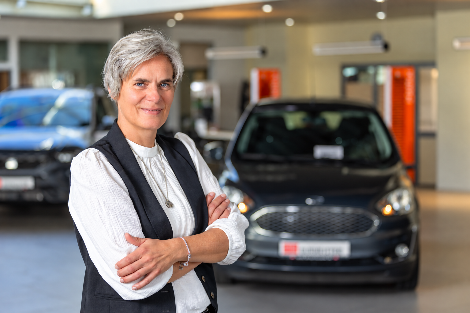 Geschäftsführerin Johanna Burmeister mit 2 Fahrzeugen im Hintergrund